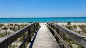 Boardwalk heading to the beach and ocean with dunes and grass on either side